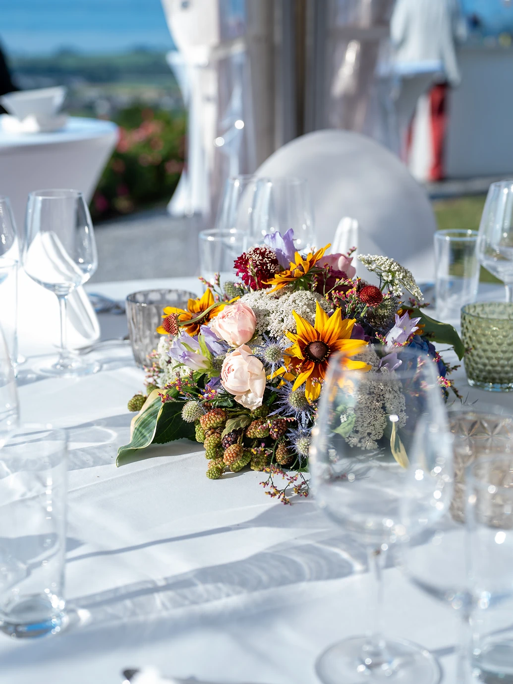 Sommerliches Blumenarrangement auf der weissen Hochzeitstafel