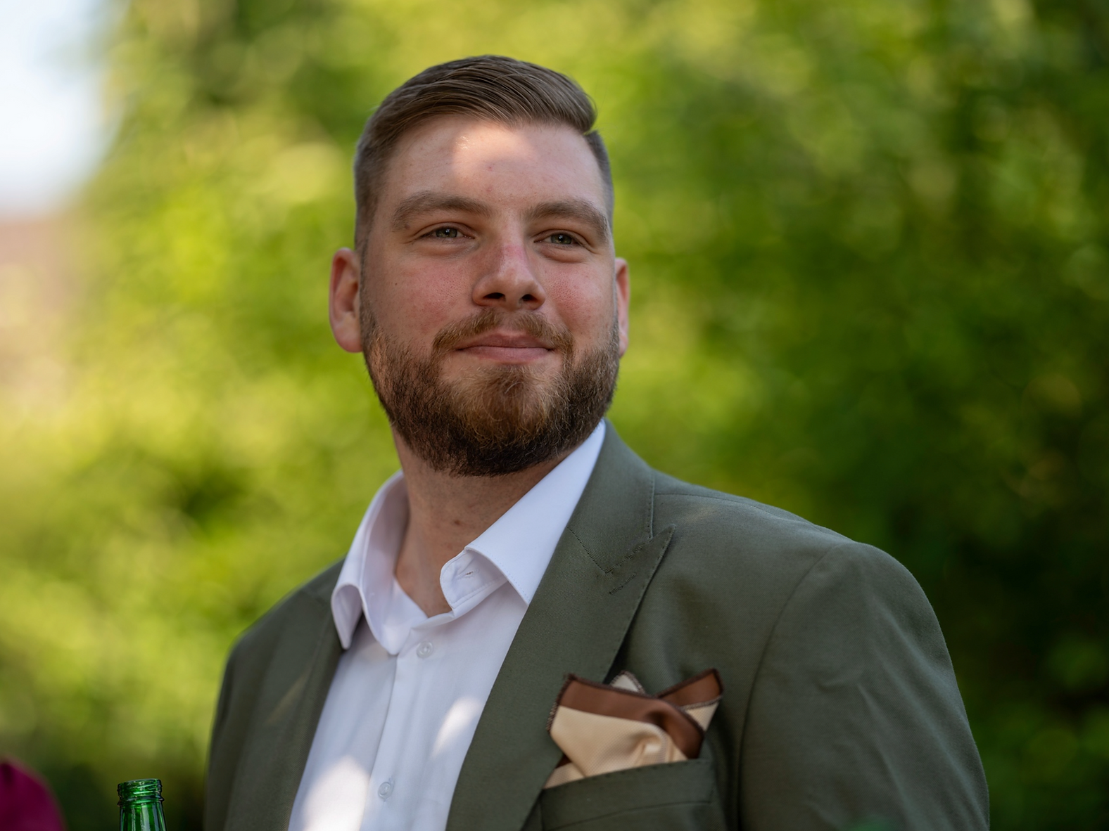 Porträt eines lächelnden Hochzeitsgastes im eleganten olivgrünen Anzug