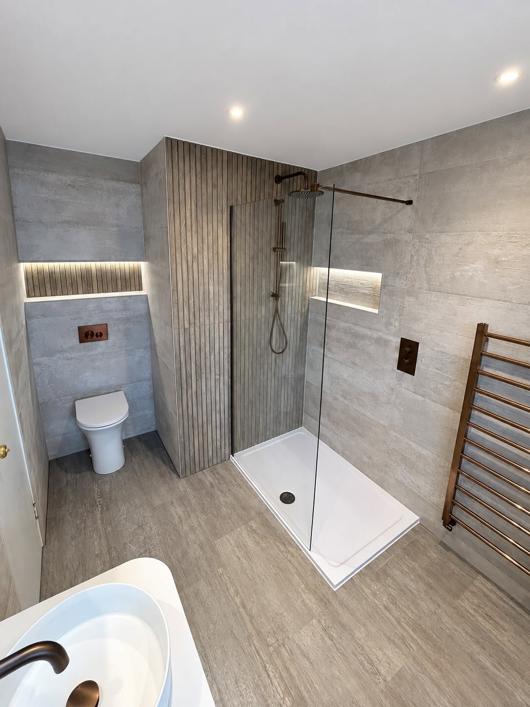Spacious walk-in wet room with slate grey porcelain tiles and bronze radiator in Renfrew