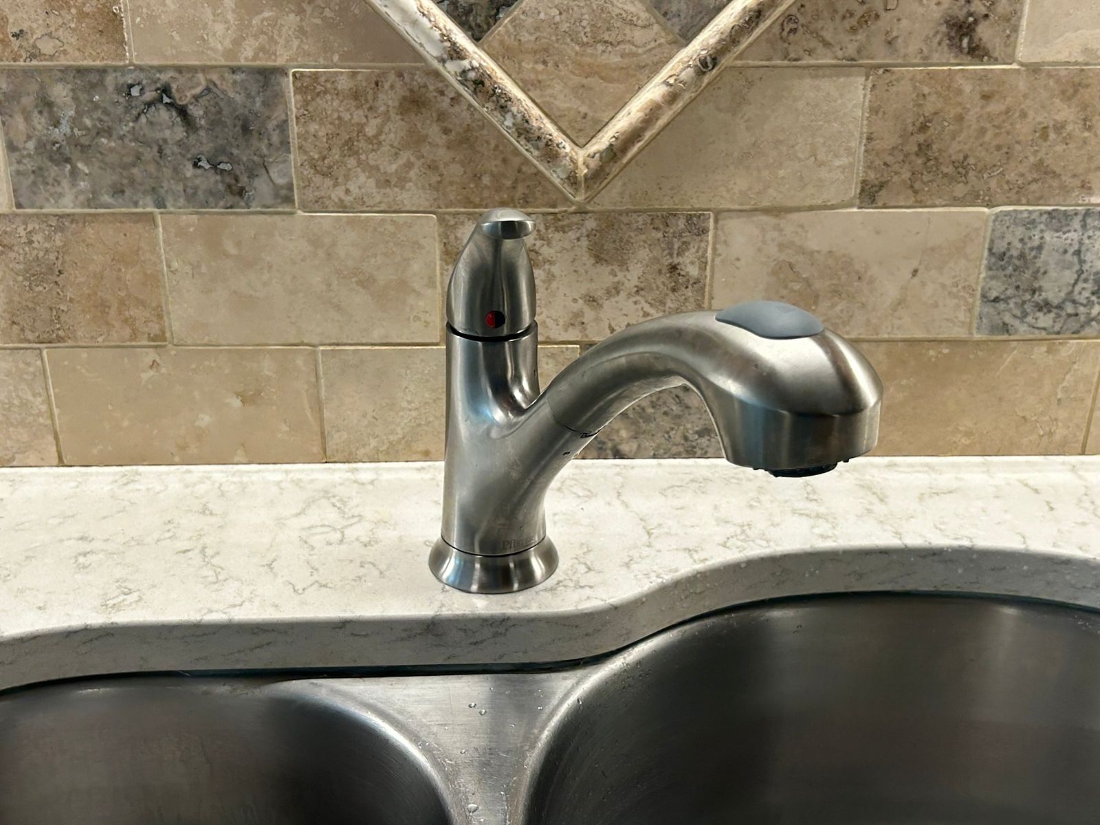 Stainless pull-out kitchen faucet installed over a double sink