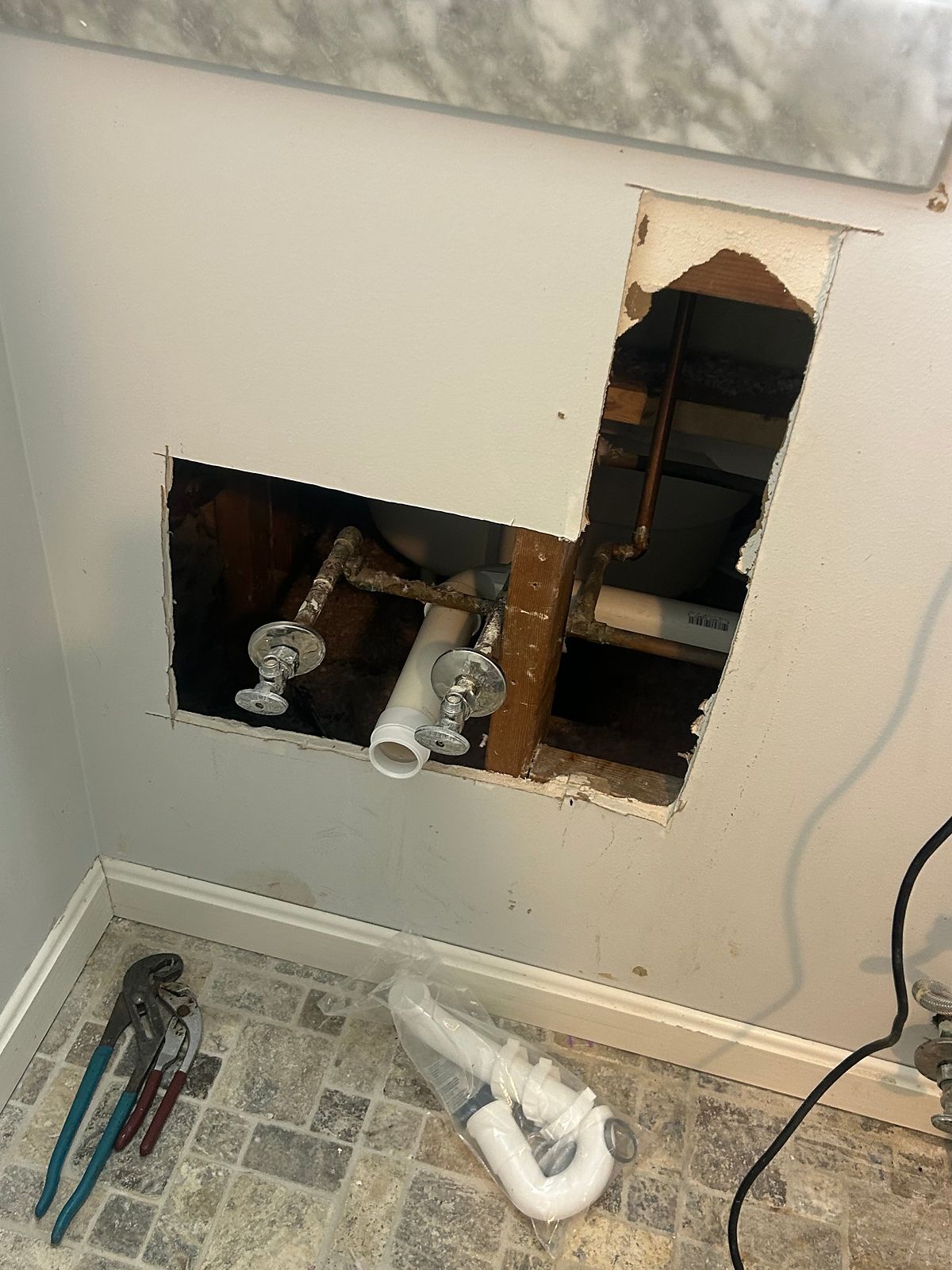 Bathroom with the walls opened behind the vanity and toilet during a drain repair