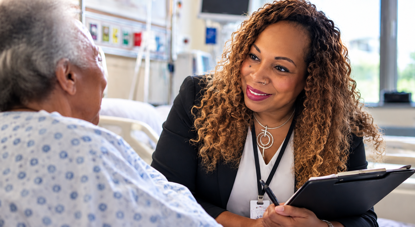 Medical social worker consulting compassionately with patient at hospital bedside.