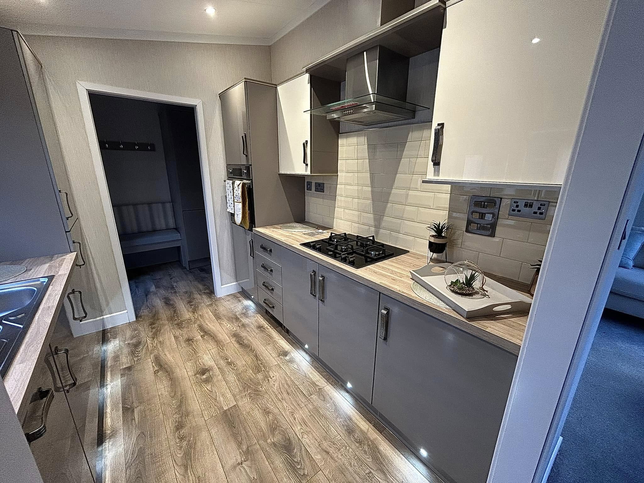 Modern fitted kitchen with gas hob, plinth lighting, integrated oven and dining area