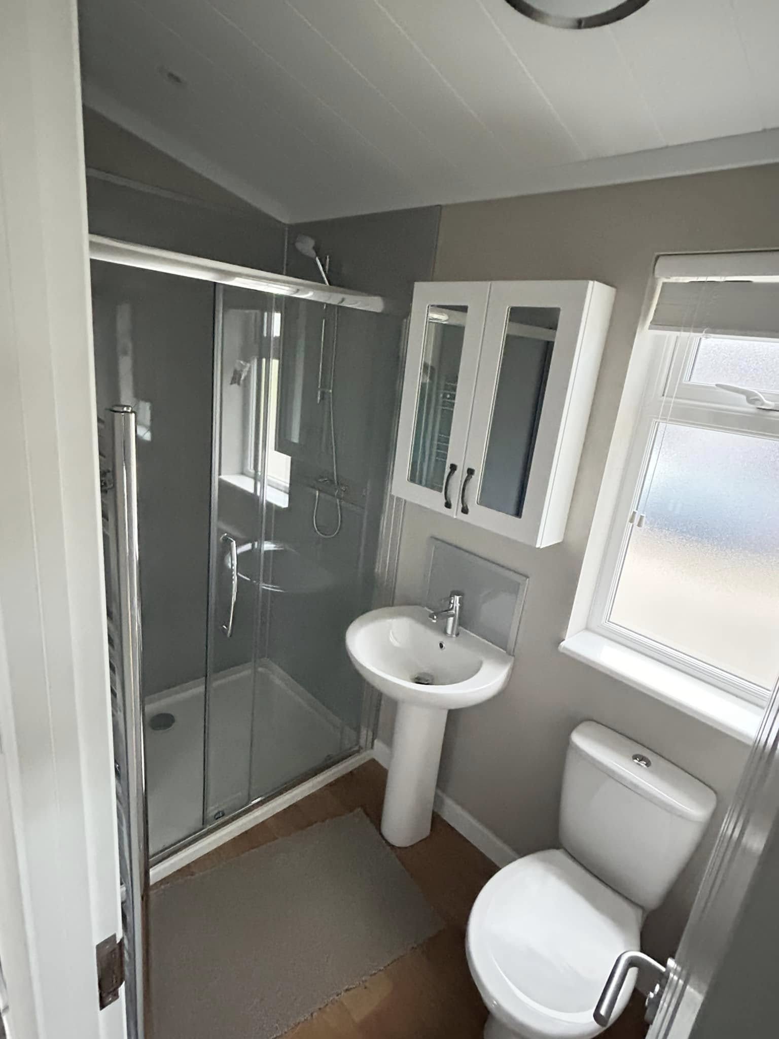 Contemporary family bathroom with glass shower enclosure and mirrored cabinet