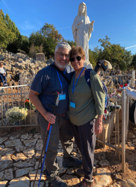 Pilgrims smiling before the statue of Our Lady of Medjugorje on Apparition Hill with walking poles