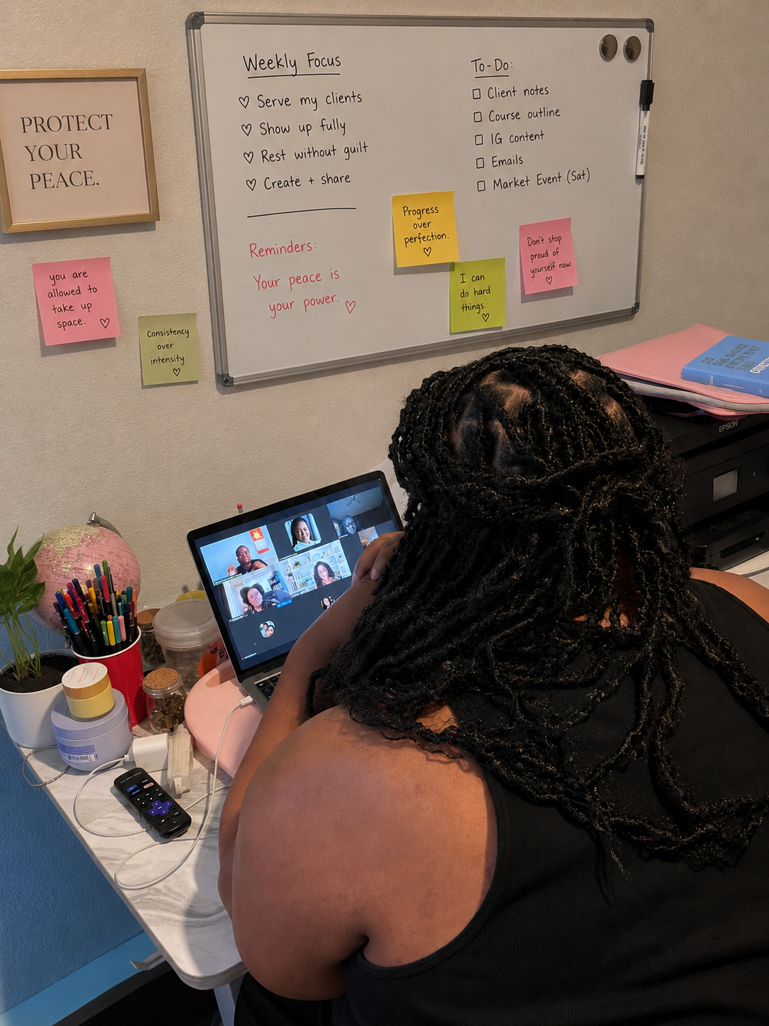 Student at her desk facing a laptop with a whiteboard reading 'Protect your peace', 'Serve my clients', 'Rest without guilt'