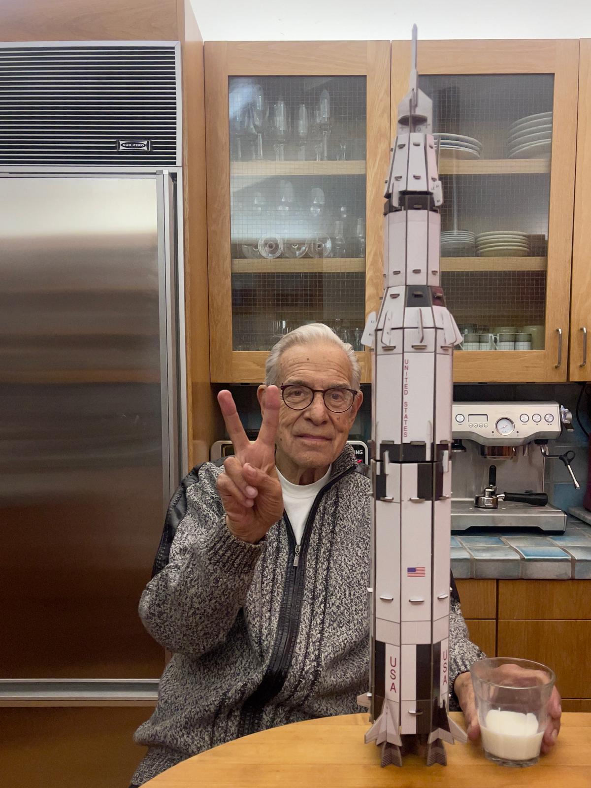 Lanny flashing a peace sign beside his handcrafted rocket model
