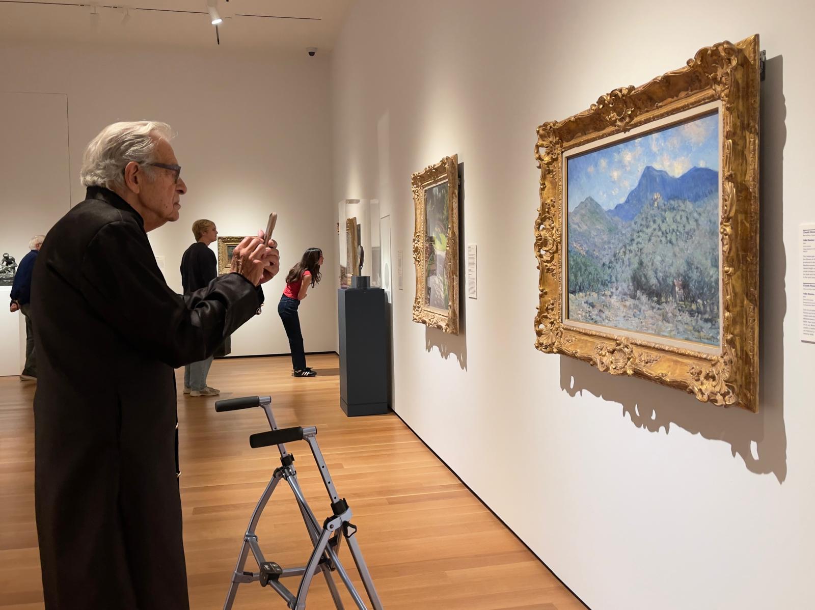 Lanny capturing an impressionist landscape painting with his phone at the art museum